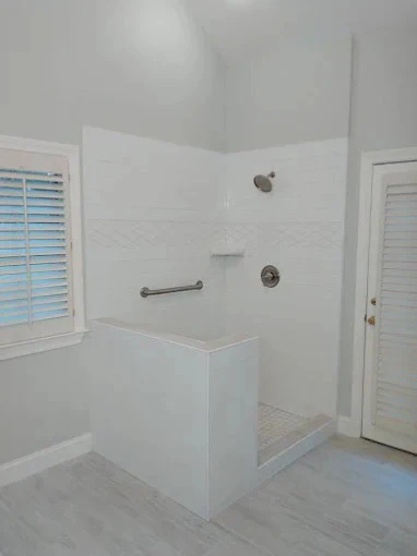 Completed accessible shower with grab bars and a built-in bench