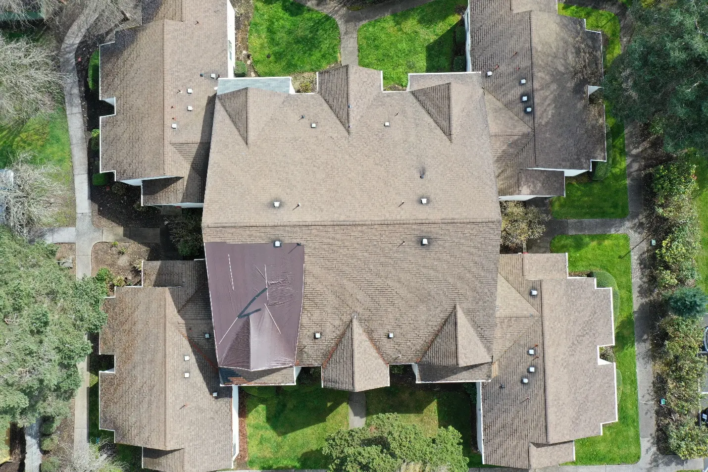 Aerial view of a multifamily roof with emergency tarping over a critical failure area