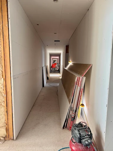 Drywall work underway in a multifamily hallway during a unit turn program